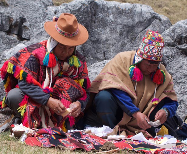 two people wearing colorful Peruvian clothes holding small objects in their hands